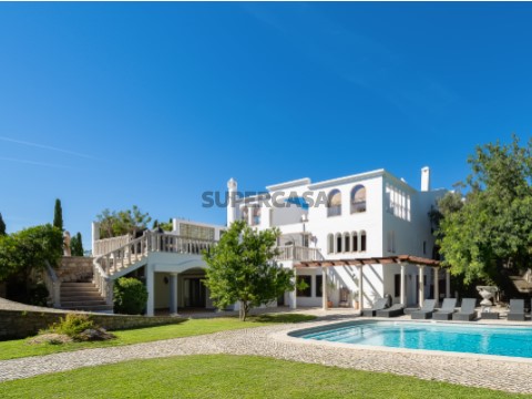Moradia moderna de luxo com piscina grande e jardim relvado sob céu azul em Carvoeiro, Algarve.