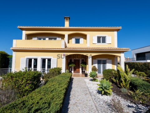Fachada de moradia T4 à venda em Lagoa, Algarve. Casa de estilo tradicional com dois pisos, jardim cuidado e caminho em calça...